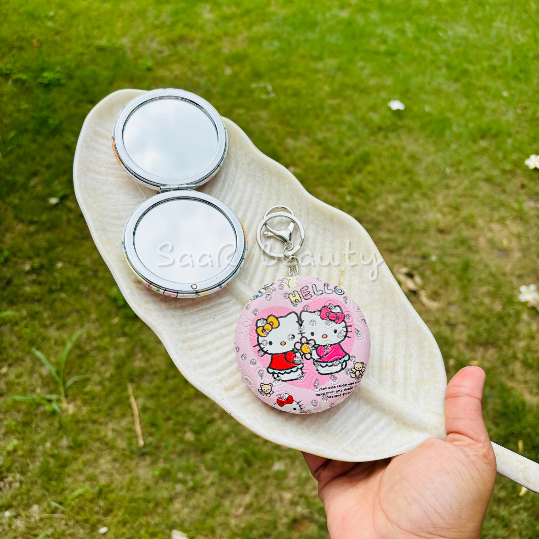 Compact mirror with cartoon character design held over grass Premium Saar Beauty keychain mirrors with Hello Kitty and Evil Eye designs – compact, portable, and durable pocket mirrors for women and girls