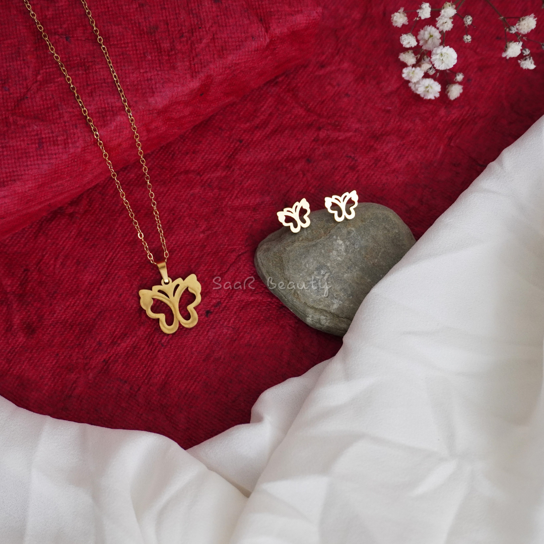 Gold-plated butterfly necklace and matching stud earrings displayed on red and white fabric.