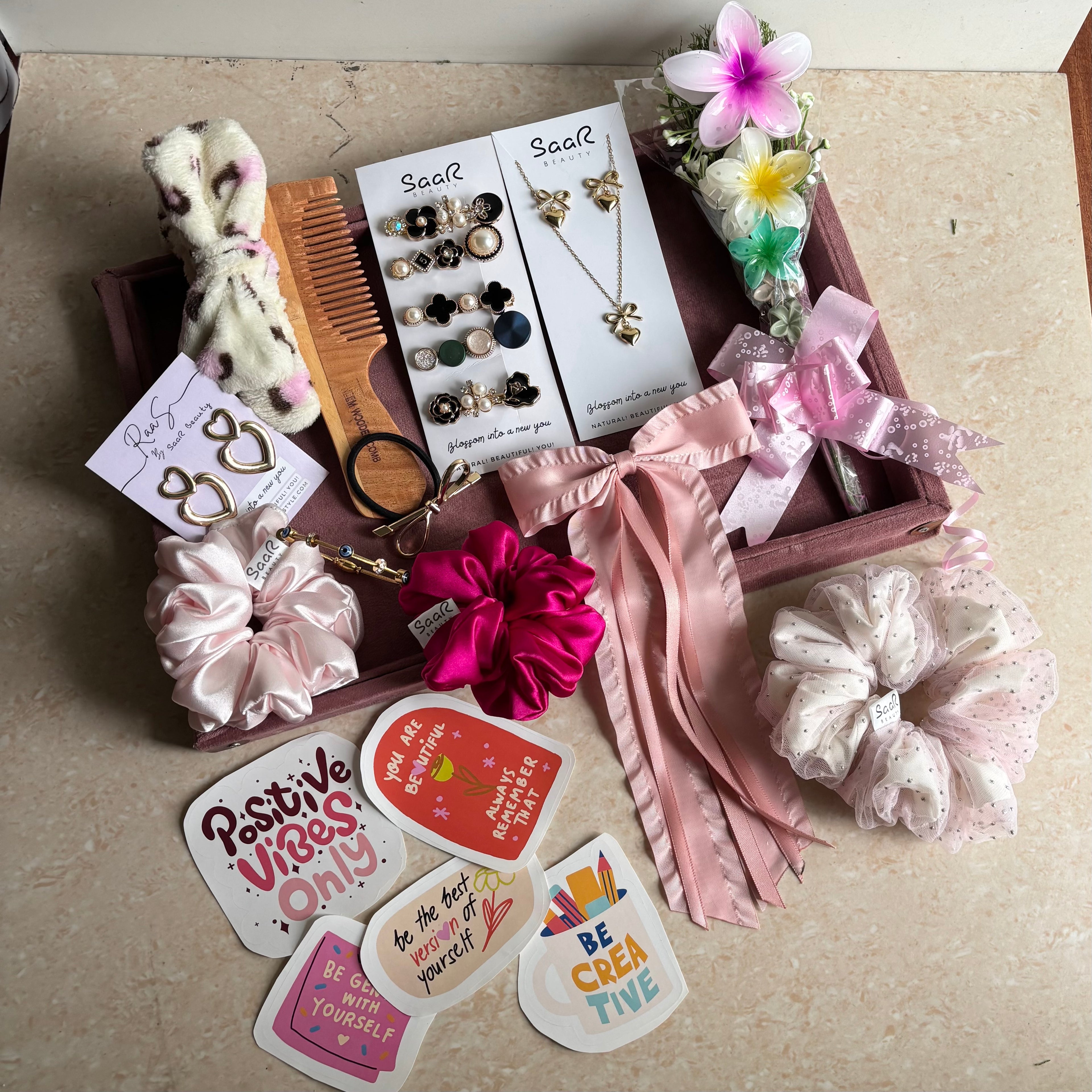 Premium Rakshabandhan gift hamper from Saar Beauty featuring satin scrunchies, anti-tarnish jewelry, flower hair clips, Korean clip set & wooden comb.
