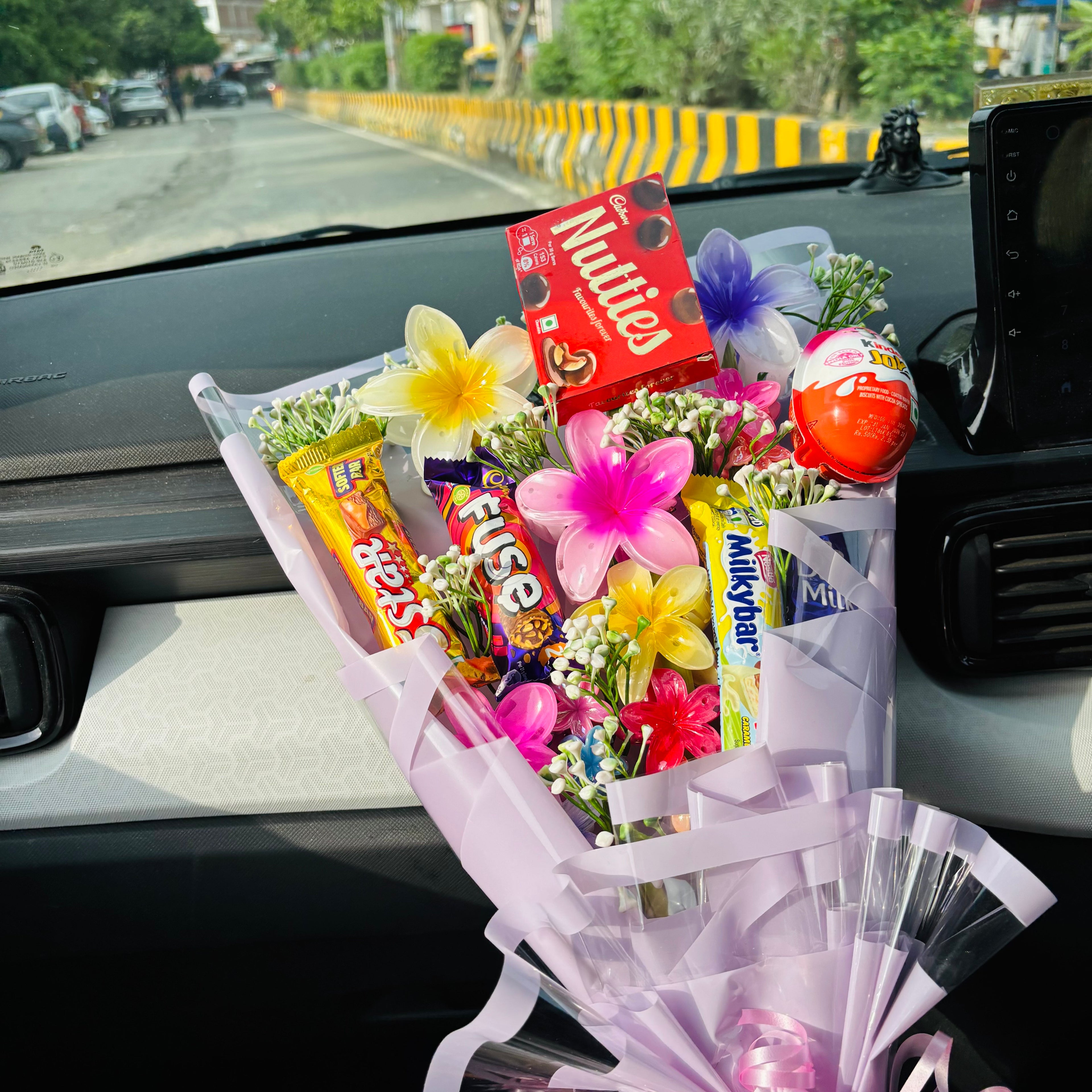 Bouquet of flowers with candy bars on a car dashboard