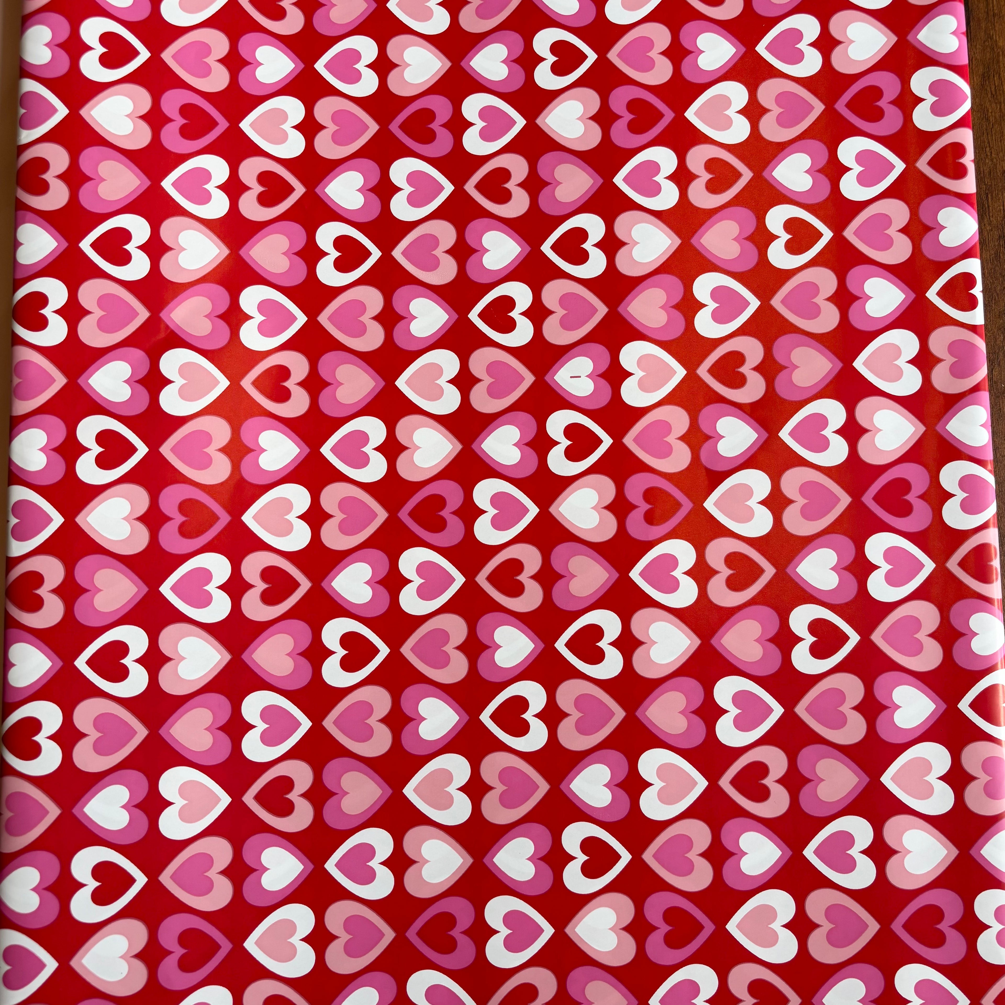 Red fabric with a pattern of pink, white, and purple hearts Bright red gift wrap with pink, red, and white heart pattern – perfect for Valentine’s Day and romantic gifts