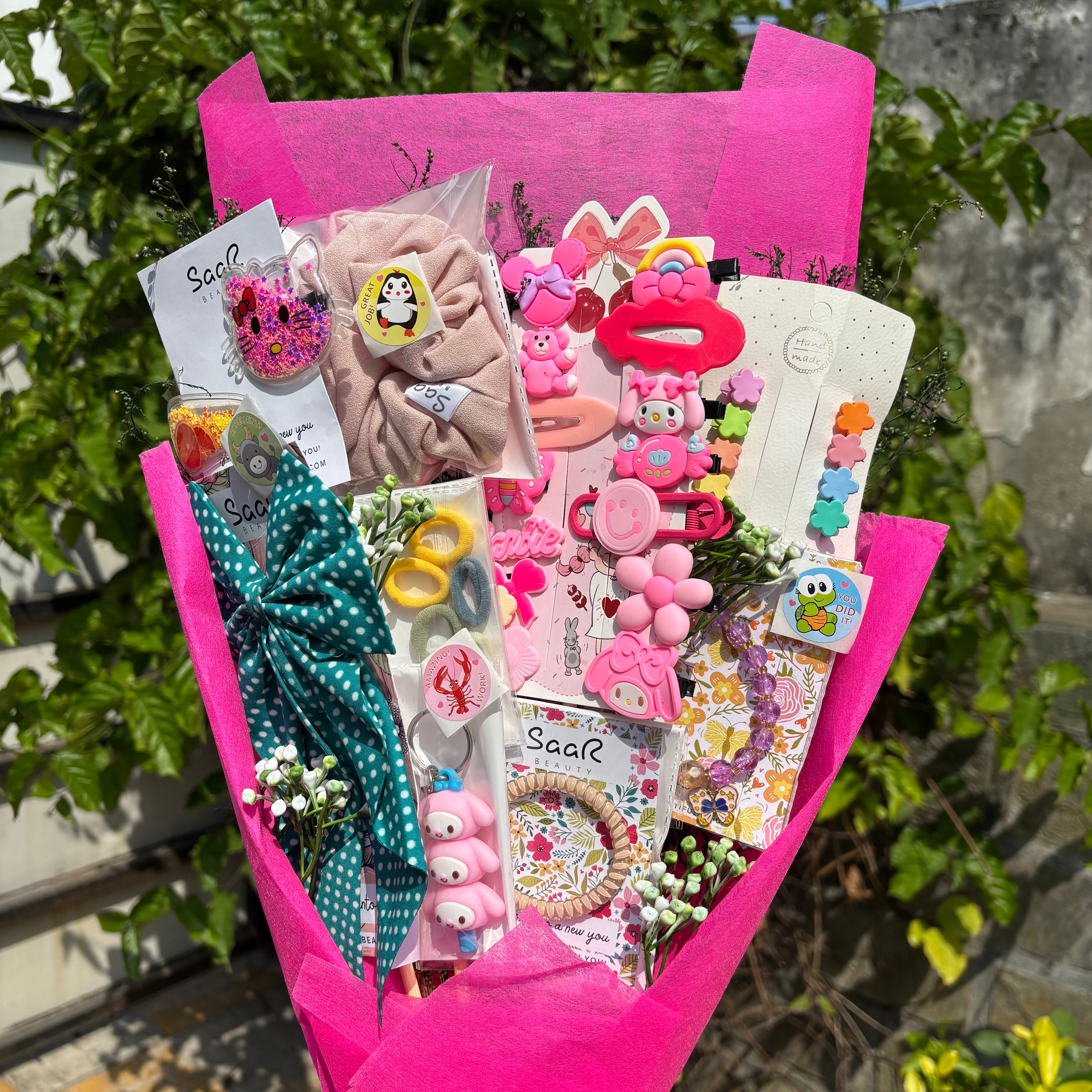 Bouquet of hair accessories including bows and clips with a pink wrap, against a natural background. Limited Edition Saar Beauty Daughters Kids Accessories Bouquet – Cute Gift Set for Little Girls with Hair Clips, Scrunchies, Bracelet & Stickers