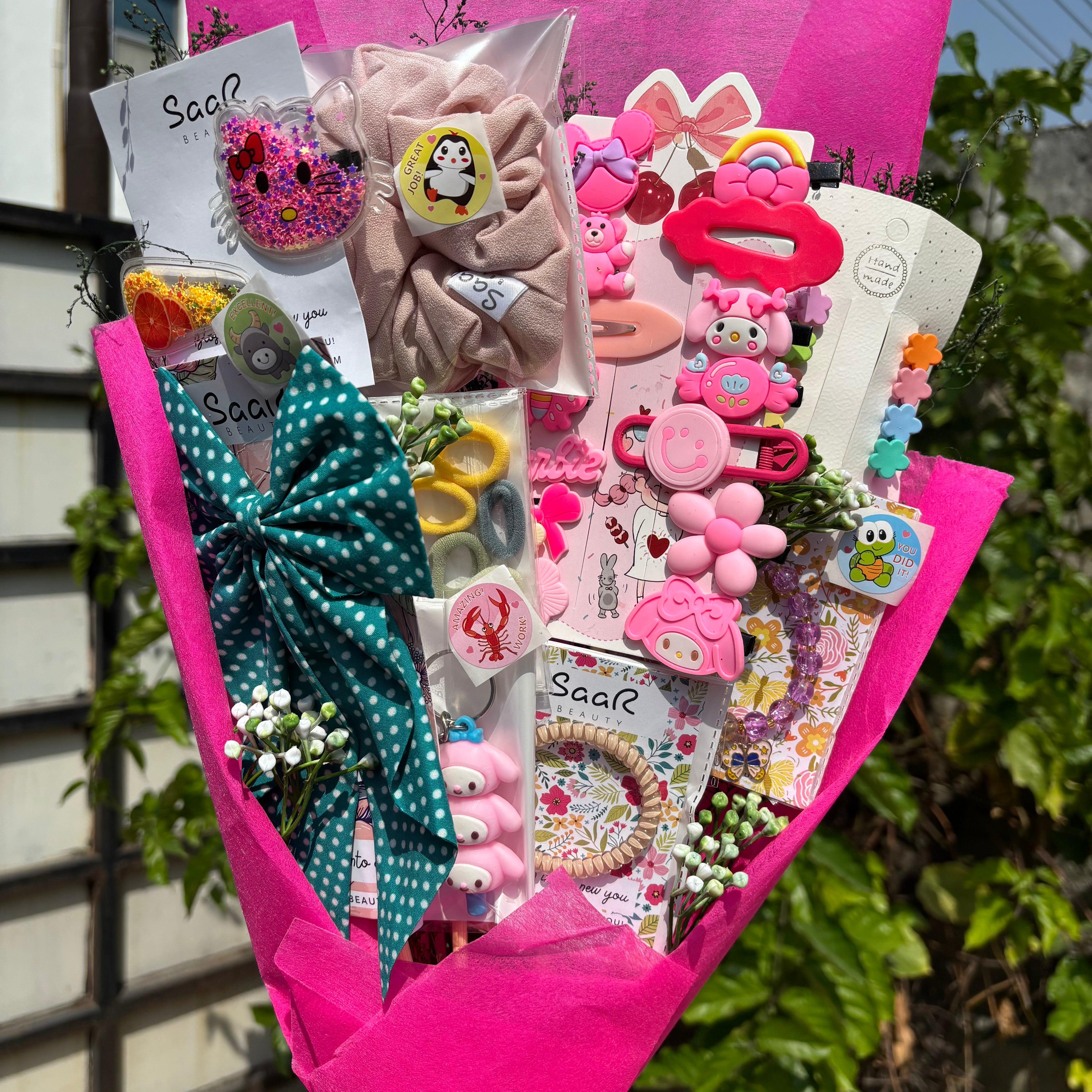 Bouquet of decorative items including bows, hair clips, and stationery in pink paper wrapping. Limited Edition Saar Beauty Daughters Kids Accessories Bouquet – Cute Gift Set for Little Girls with Hair Clips, Scrunchies, Bracelet & Stickers