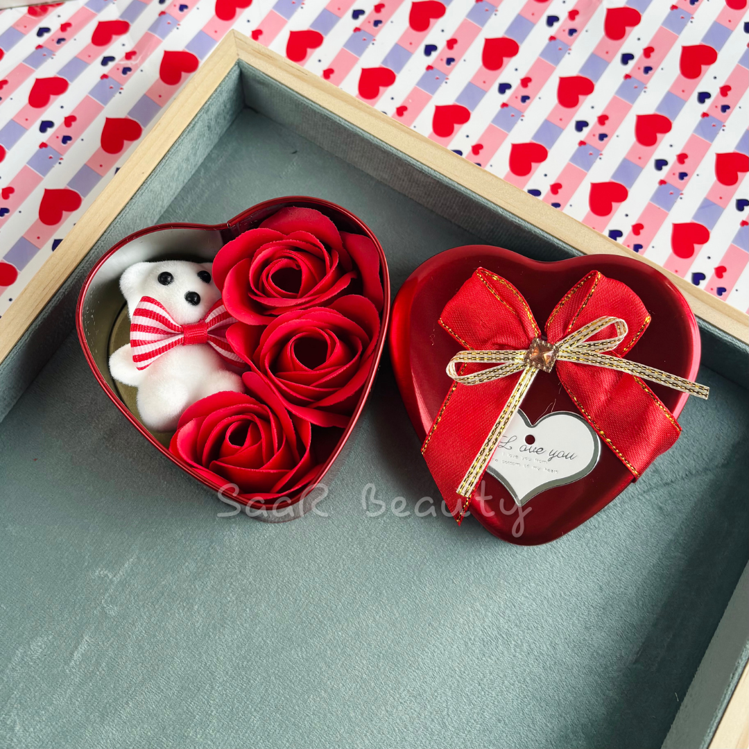 Medium-sized heart-shaped gift box with a plush teddy bear, artificial roses, a satin ribbon, and a love tag—ideal for romantic occasions and gifting.