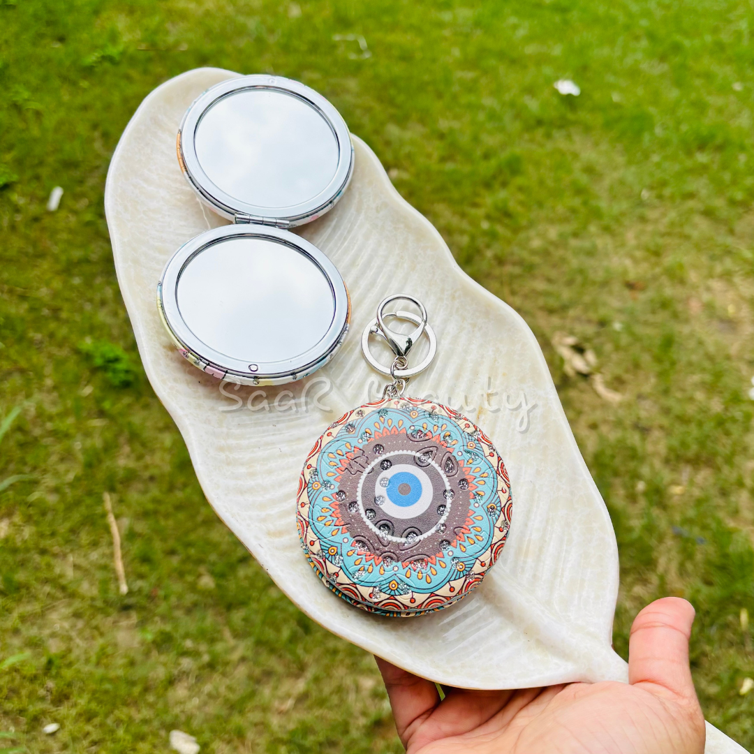 Decorative compact mirror with keychain on a leaf against a grassy Premium Saar Beauty keychain mirrors with Hello Kitty and Evil Eye designs – compact, portable, and durable pocket mirrors for women and girls background