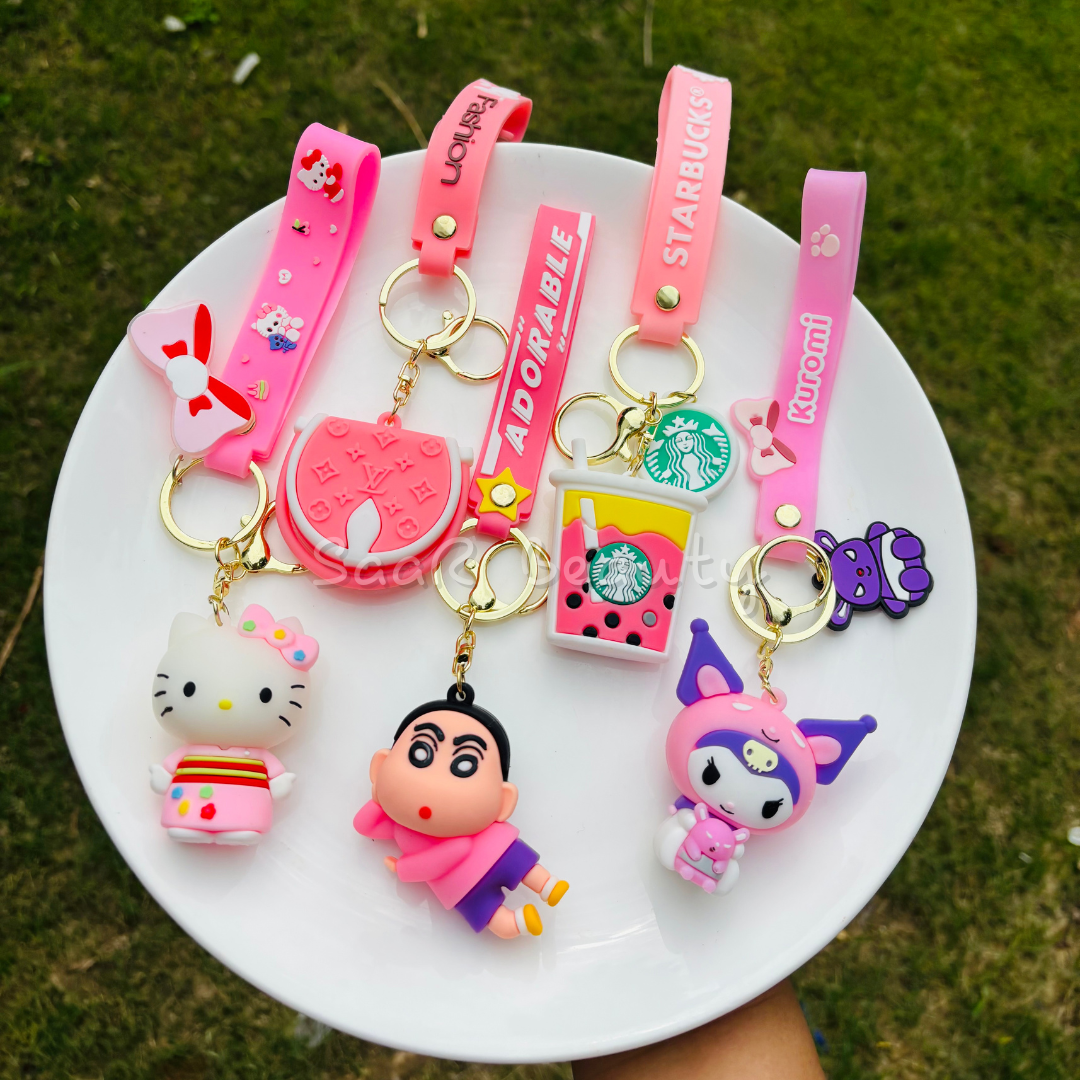 Premium cute cartoon keychains by Saar Beauty featuring Hello Kitty, Shinchan, Kuromi, Starbucks drink, boba tea, and pink bow designs – durable, trendy, and stylish for women, kids, and girl.Collection of colorful keychains on a white plate with a grassy background