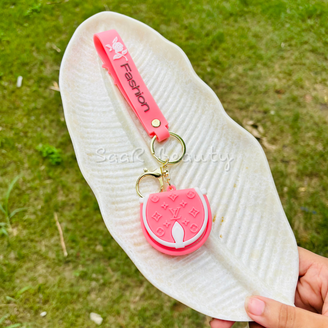 Premium cute cartoon keychains by Saar Beauty featuring Hello Kitty, Shinchan, Kuromi, Starbucks drink, boba tea, and pink bow designs – durable, trendy, and stylish for women, kids, and girl Pink keychain with a small pouch attached to a white insole on a grassy background.