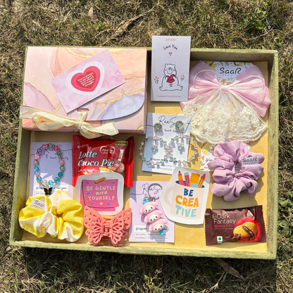 Gift box with stationery items, snacks, and decorative elements on a grassy Saar Beauty luxury light gift hamper for girls with accessories and chocolates
Premium light gift hamper for women with jewellery and cute accessories background 