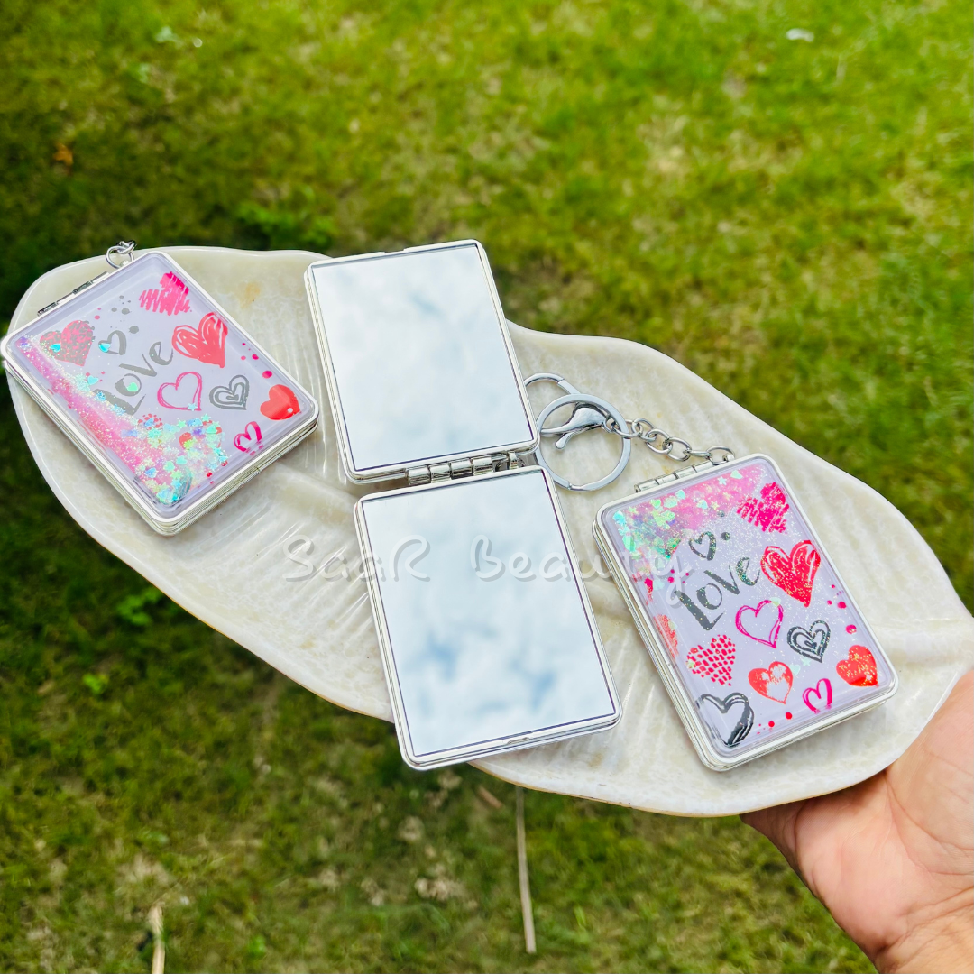 Compact mirror with decorative case held over a green grass background