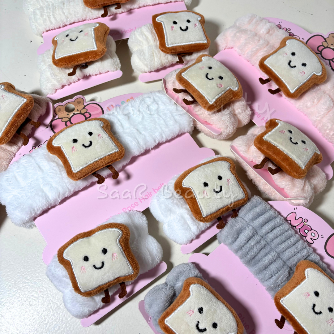 Plush toys shaped like bread with smiley faces on a pink tray.