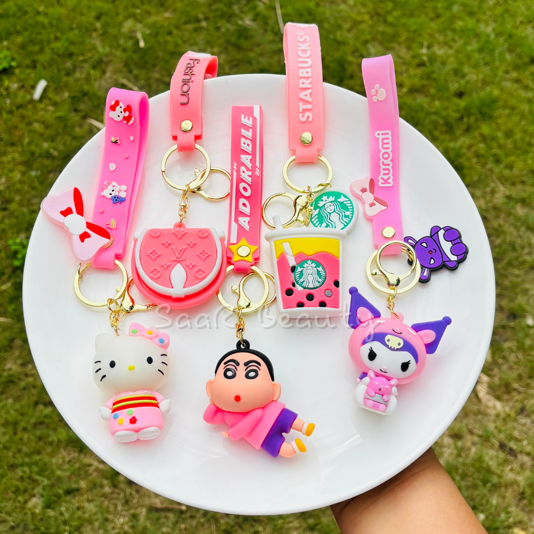 Premium cute cartoon keychains by Saar Beauty featuring Hello Kitty, Shinchan, Kuromi, Starbucks drink, 
 boba tea, and pink bow designs – durable, trendy, and stylish for women, kids, and girlCollection of colorful keychains on a white plate with a grassy background
