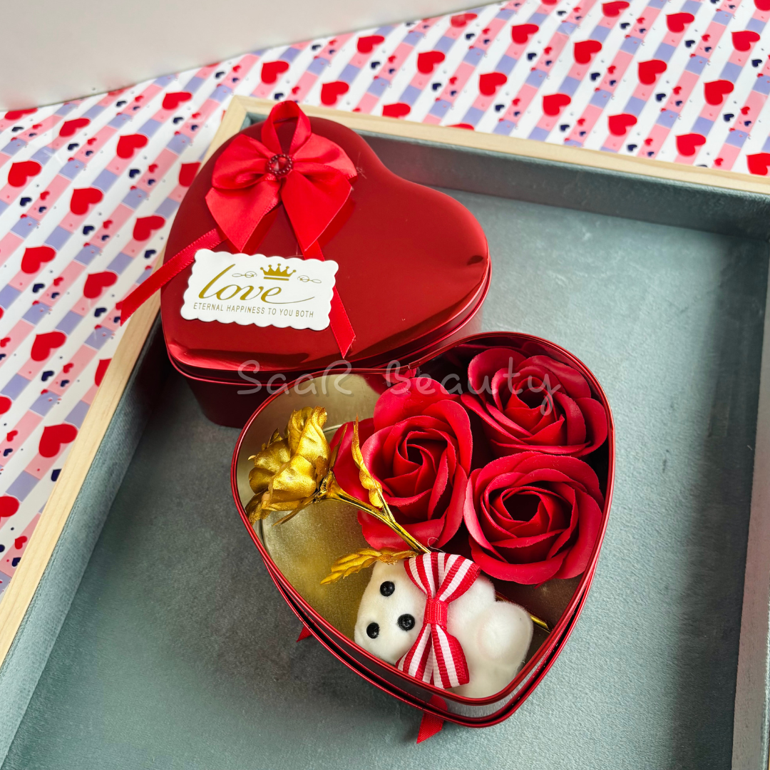 Heart-shaped Valentine’s Day gift box with artificial roses, a small teddy bear, a golden rose, and a decorative ribbon—perfect for romantic occasions.