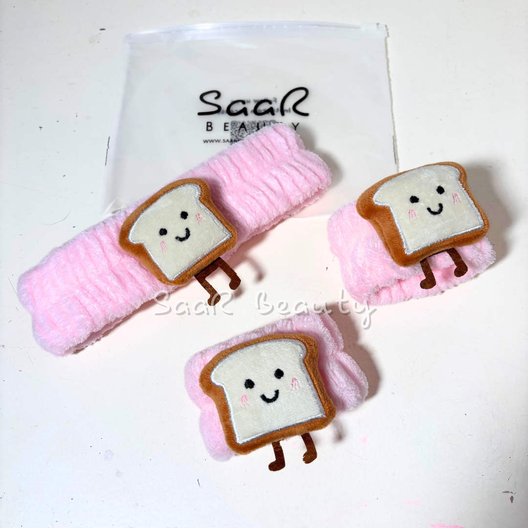 Set of bread-shaped hair clips with pink ribbons on a white background, branded 'Saar Beauty'.