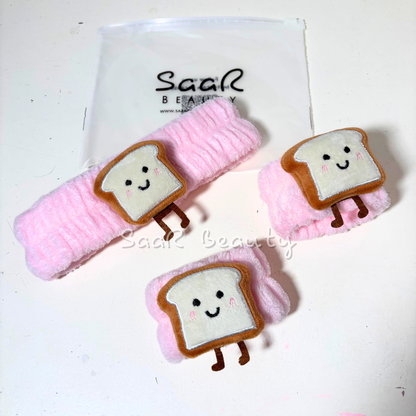 Set of bread-shaped hair clips with pink ribbons on a white background, branded 'Saar Beauty'.
