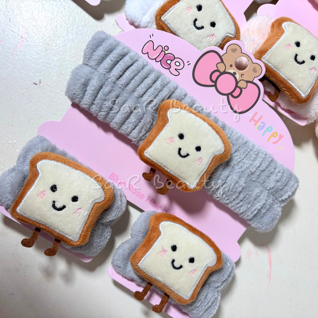 Plush toast-shaped hair clips with smiling faces on a pink card with cartoon character. Pink plush skincare headband with bread design and water-absorbing hand wraps