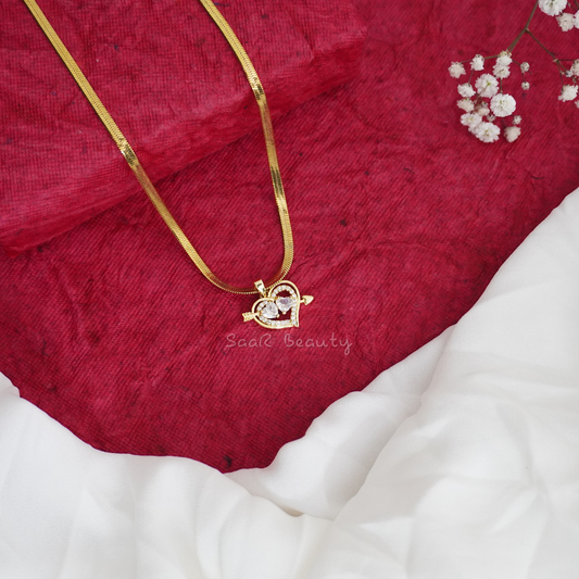 A gold snake chain necklace with a glossy white heart pendant.