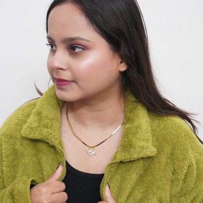 A model wearing a gold snake chain necklace with a glossy white heart pendant, paired with a green fleece jacket.
Close-up of a woman styled with a minimalist gold necklace featuring a white pearl heart charm, perfect for casual or formal wear.
A chic gold chain necklace with a white heart pendant, worn by a model in a cozy, casual outfit.
