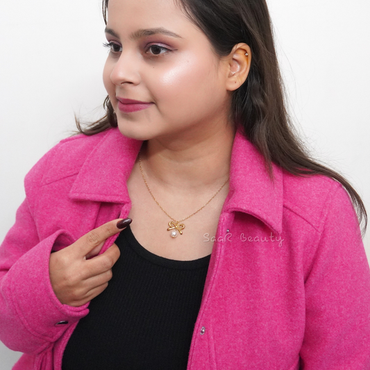 Model wearing Gold bow-shaped charm necklace with a hanging pearl by SaaR Beauty, featuring a delicate and anti-tarnish waterproof stainless steel design.