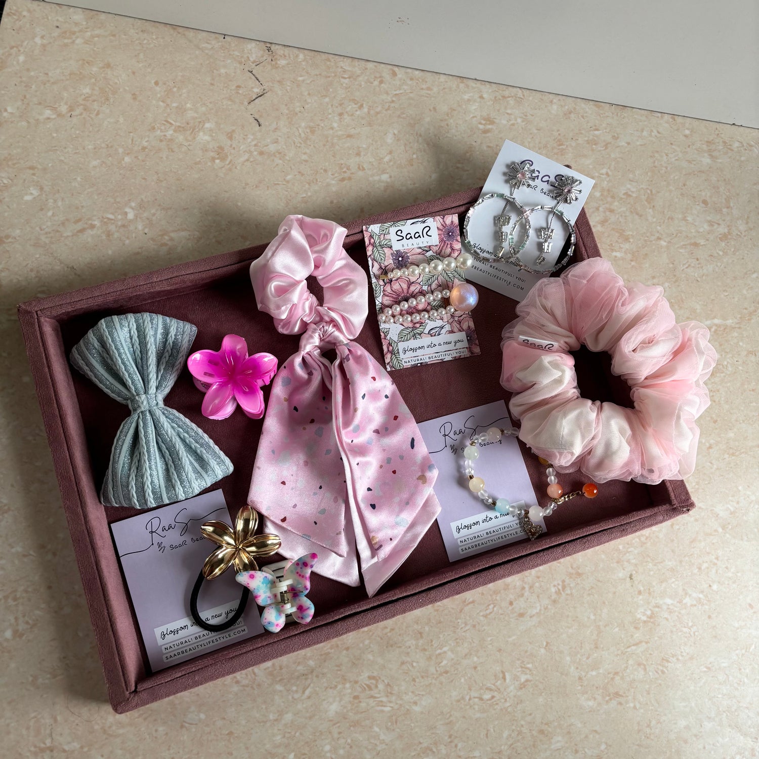 Premium Rakshabandhan gift box with shimmer bow, satin scarf scrunchie, flower hair claw, butterfly clip, jewelry, and hair accessories by Saar Beauty.