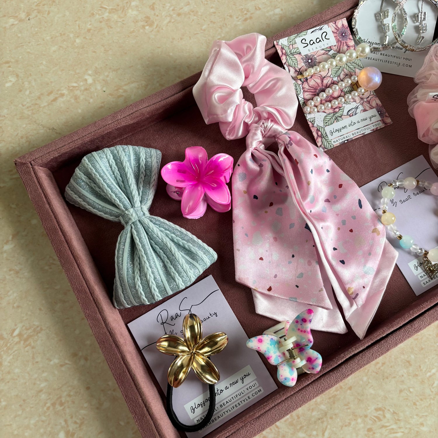 Premium Rakshabandhan gift box with shimmer bow, satin scarf scrunchie, flower hair claw, butterfly clip, jewelry, and hair accessories by Saar Beauty.