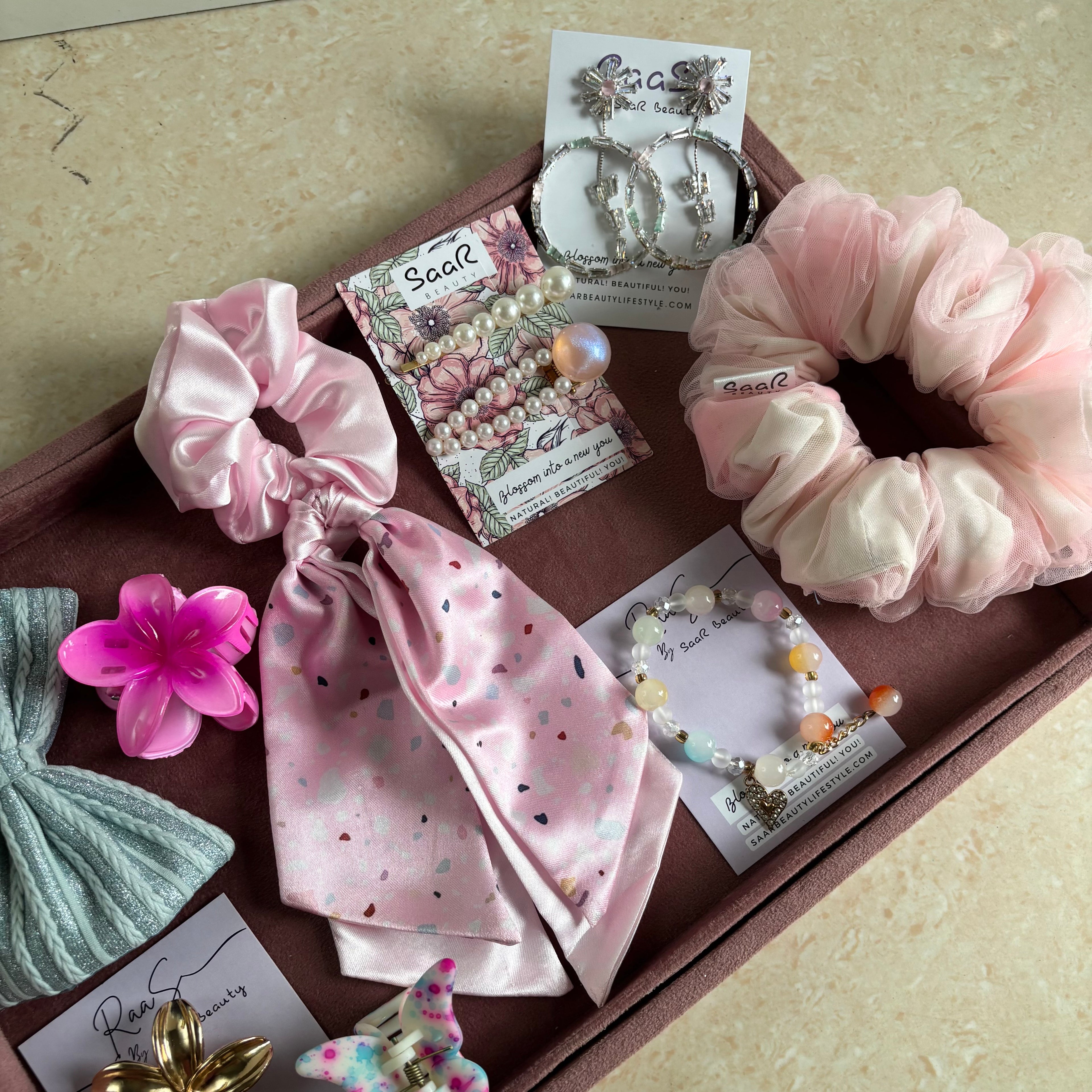 Premium Rakshabandhan gift box with shimmer bow, satin scarf scrunchie, flower hair claw, butterfly clip, jewelry, and hair accessories by Saar Beauty.