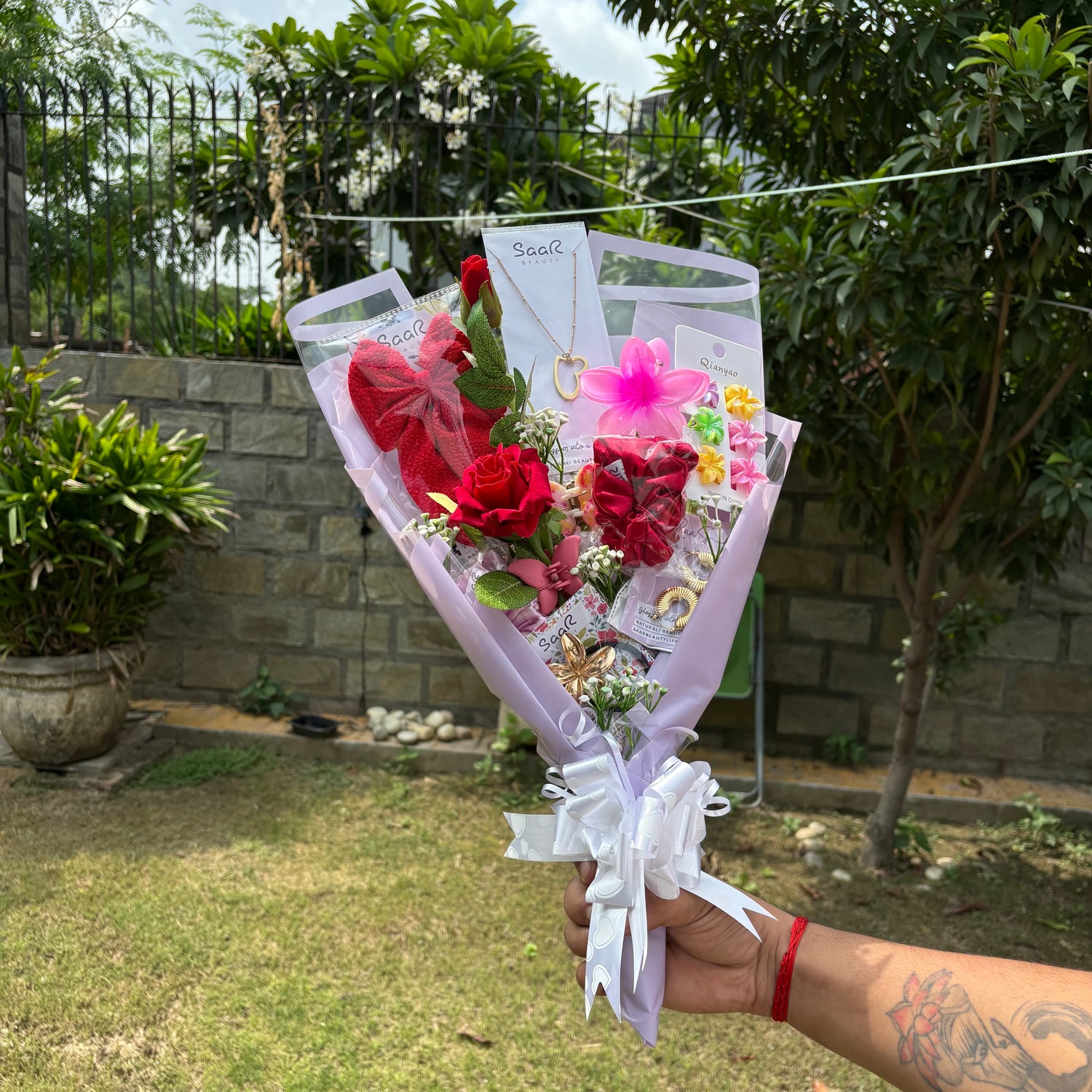 Bouquet of flowers held by a person outdoors with greenery in the background