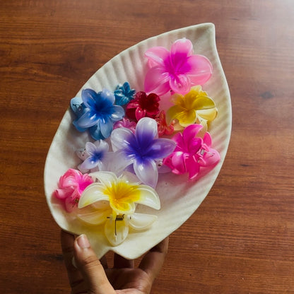 Colorful flower-shaped hair clips on a leaf-shaped holder against a wooden background. Premium Saar Beauty hair claw & chocolate bouquet with assorted flower clutchers for thick and long hair – perfect birthday gift for women and girls.