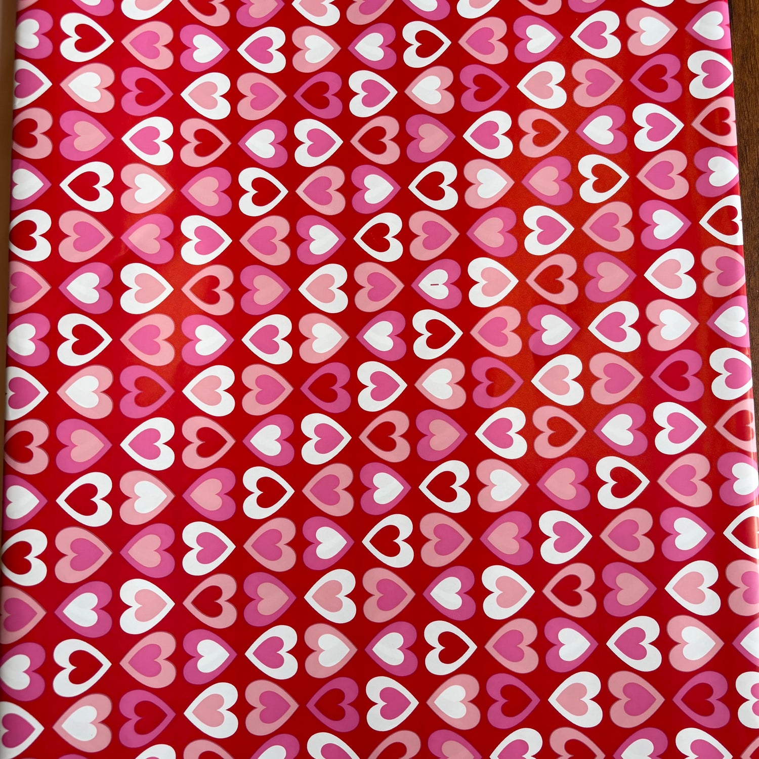 Red fabric with a pattern of pink, white, and purple hearts Bright red gift wrap with pink, red, and white heart pattern – perfect for Valentine’s Day and romantic gifts