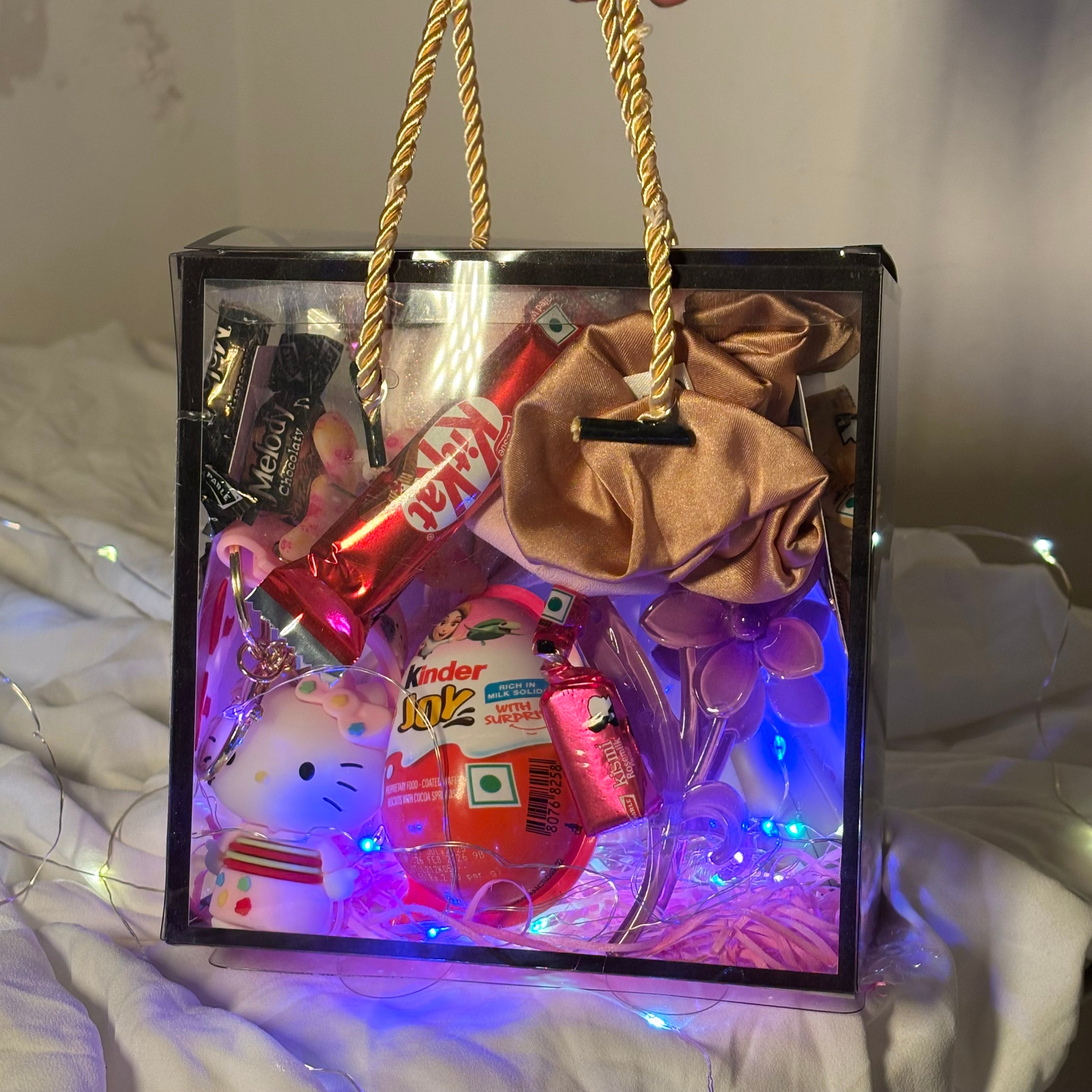 Gift hamper for women with earrings, scrunchies, clutchers and Kinder Joy Decorative gift bag with snacks and a Hello Kitty figurine on a soft surface.