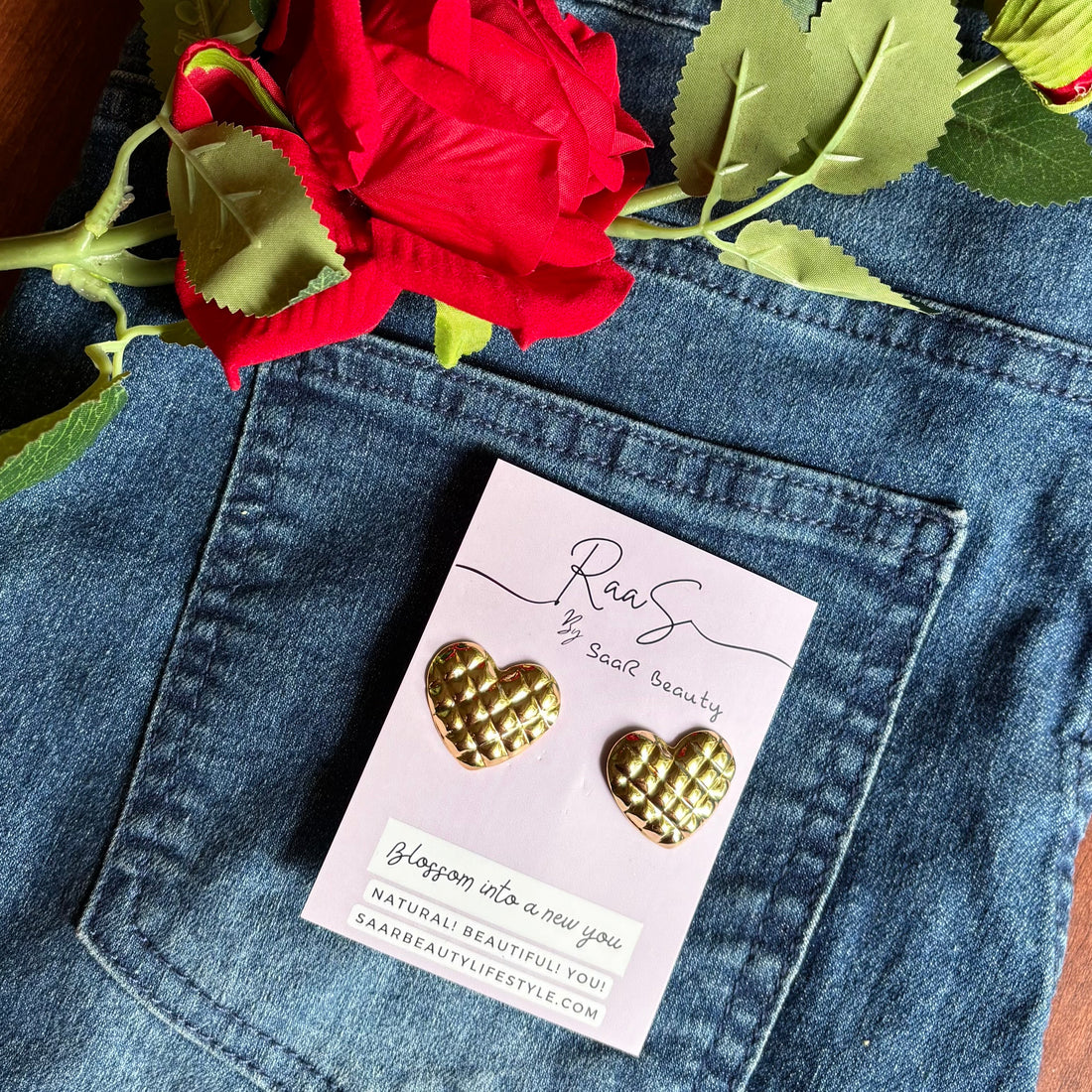 Gold heart-shaped earrings on a card with a red rose and denim Trendy quilted heart design stud earrings for women background
