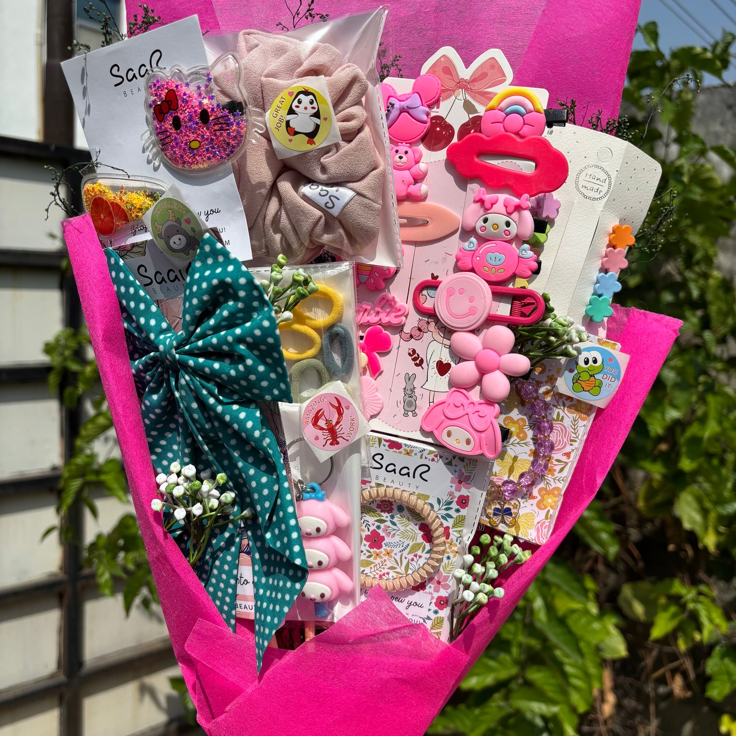 Bouquet of decorative items including bows, hair clips, and stationery in pink paper wrapping. Limited Edition Saar Beauty Daughters Kids Accessories Bouquet – Cute Gift Set for Little Girls with Hair Clips, Scrunchies, Bracelet &amp; Stickers