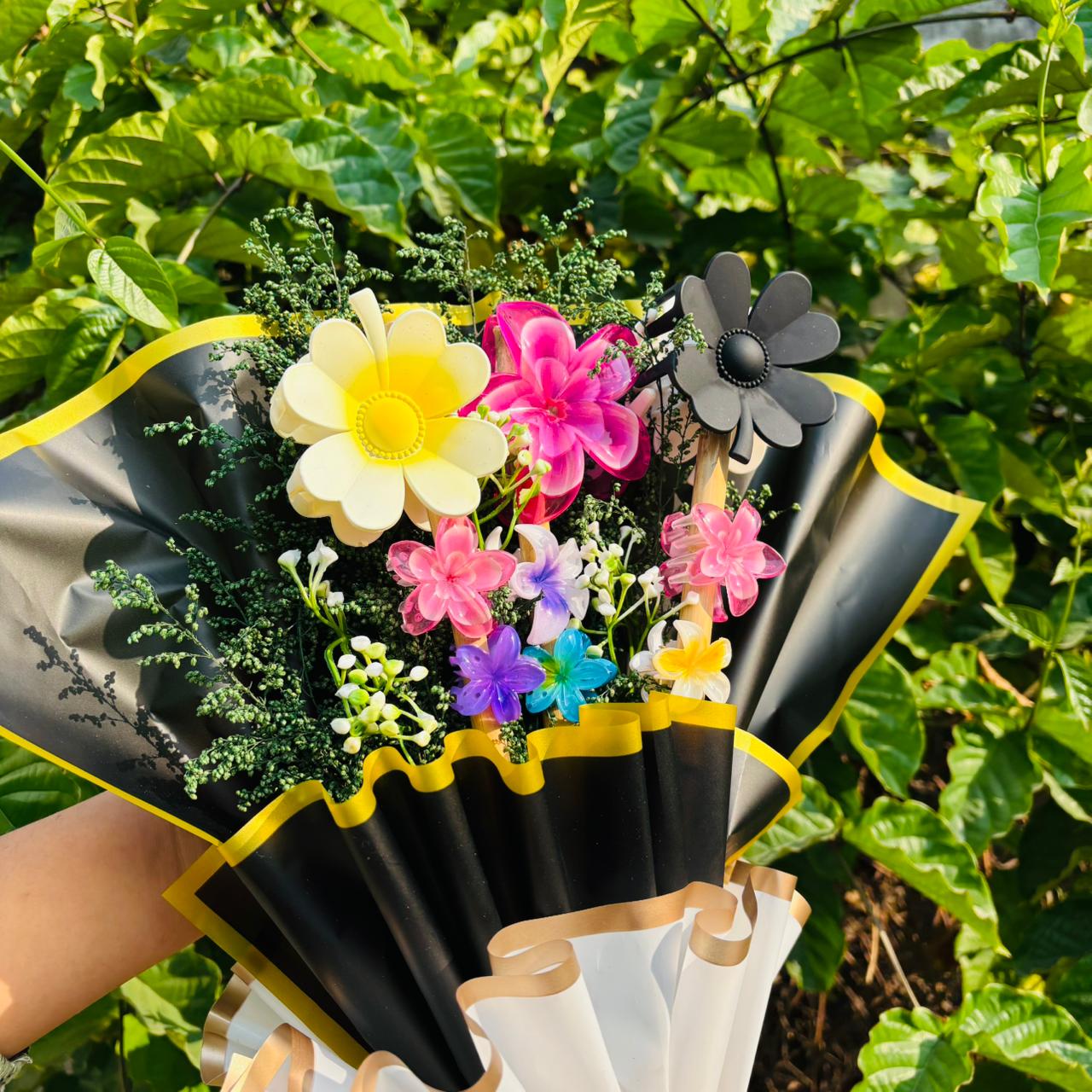 Bouquet of artificial flowers in black and yellow wrap with greenery in the background Limited Edition Saar Beauty Hair Clutcher Bouquet – Unique floral gift with 9 colorful hair claw clips beautifully wrapped for women and girls.