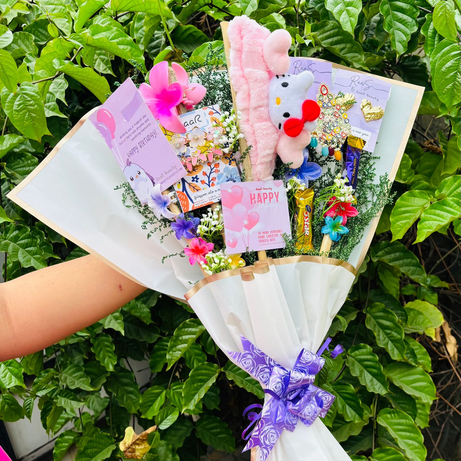 Bouquet with plush toys and flowers against a green leafy background Saar Beauty Limited Edition Birthday Accessories Bouquet – unique floral gift bouquet with hair clutchers, earrings, chocolates, and accessories for women and girl